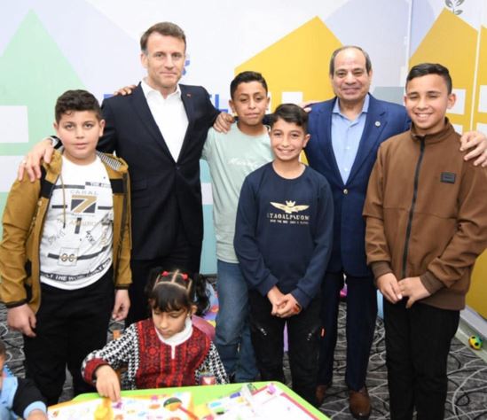 الرئيسان السيسي وماكرون يداعبان أطفالا فلسطينيين أثناء مباراة بلايستيشن بين طفلين بمنتخبي مصر وفرنسا