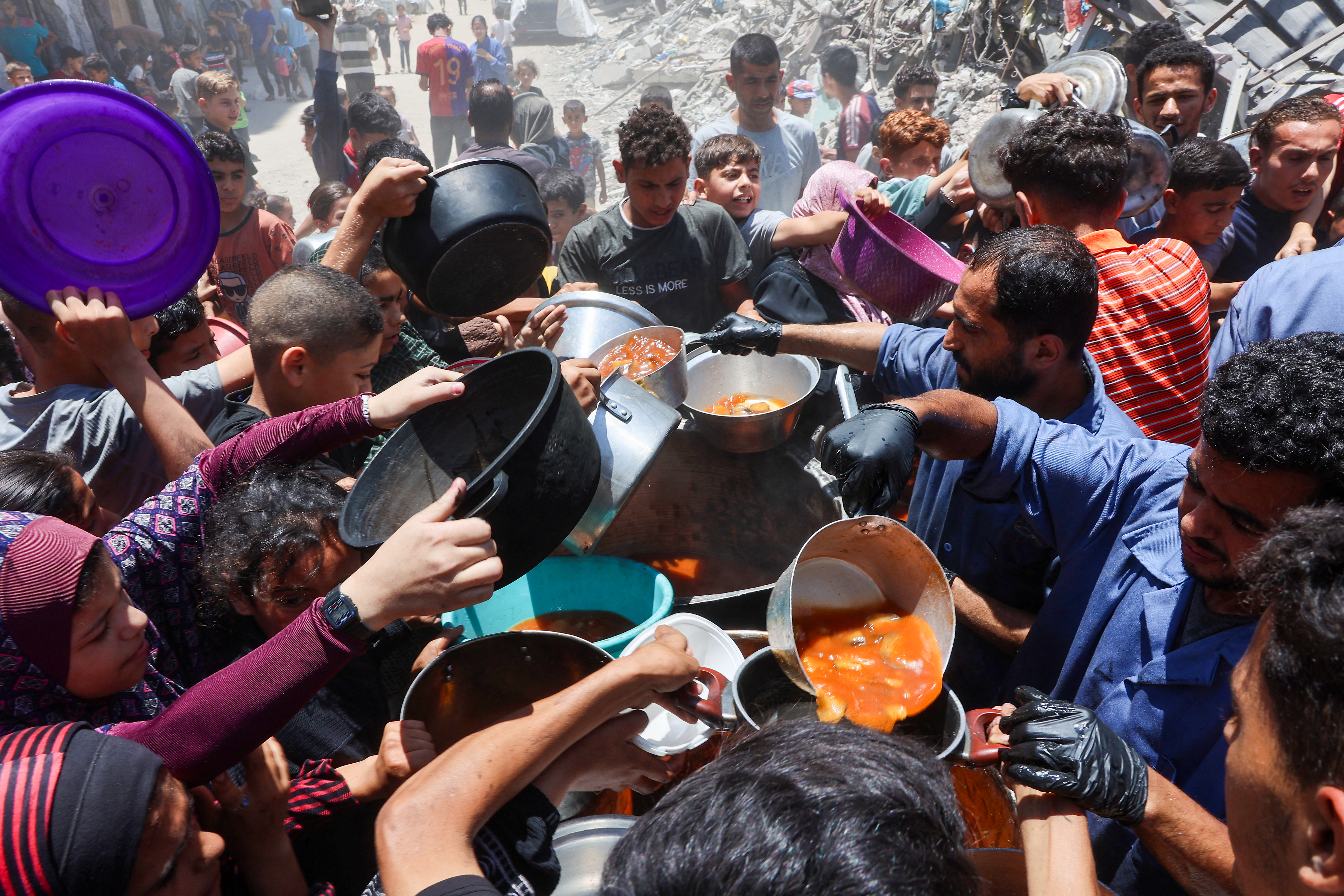 فلسطينيون يحاولون الحصول على الطعام من مطبخ خيري يقدم وجبات ساخنة في حي الرمال بمدينة غزة في 18 يونيو 2025 (أ ف ب)