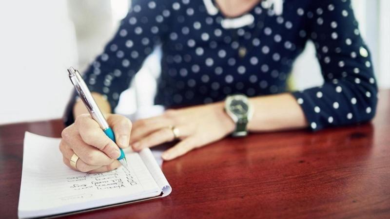 فتاة تكتب بالقلم بالإنجليزية على كراسة