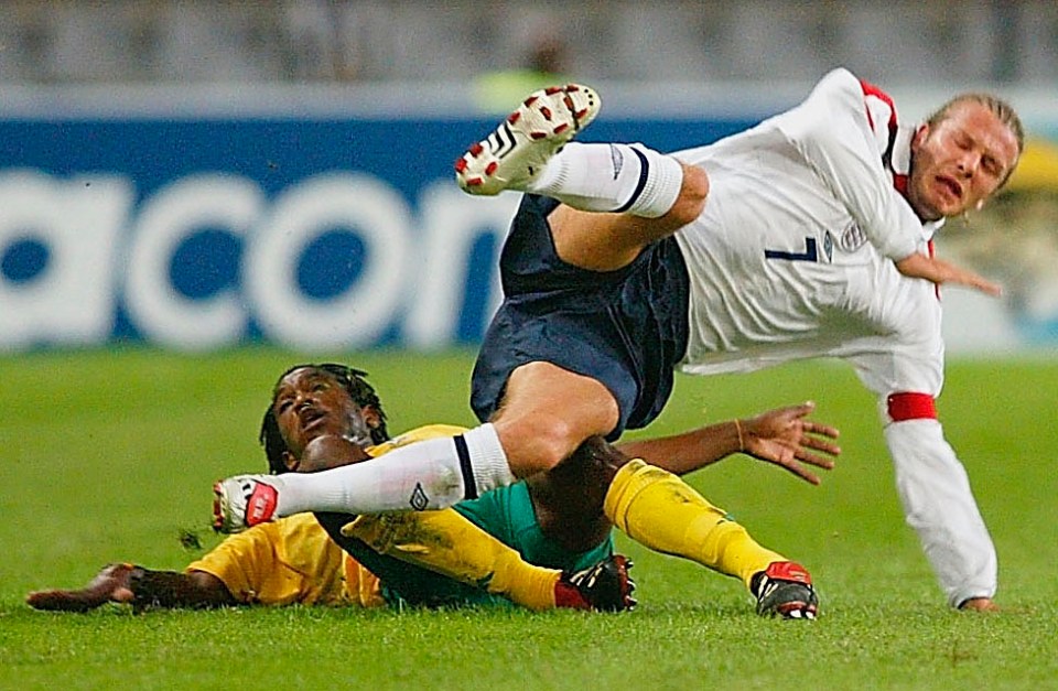 David Beckham of England being tackled during a soccer match.
