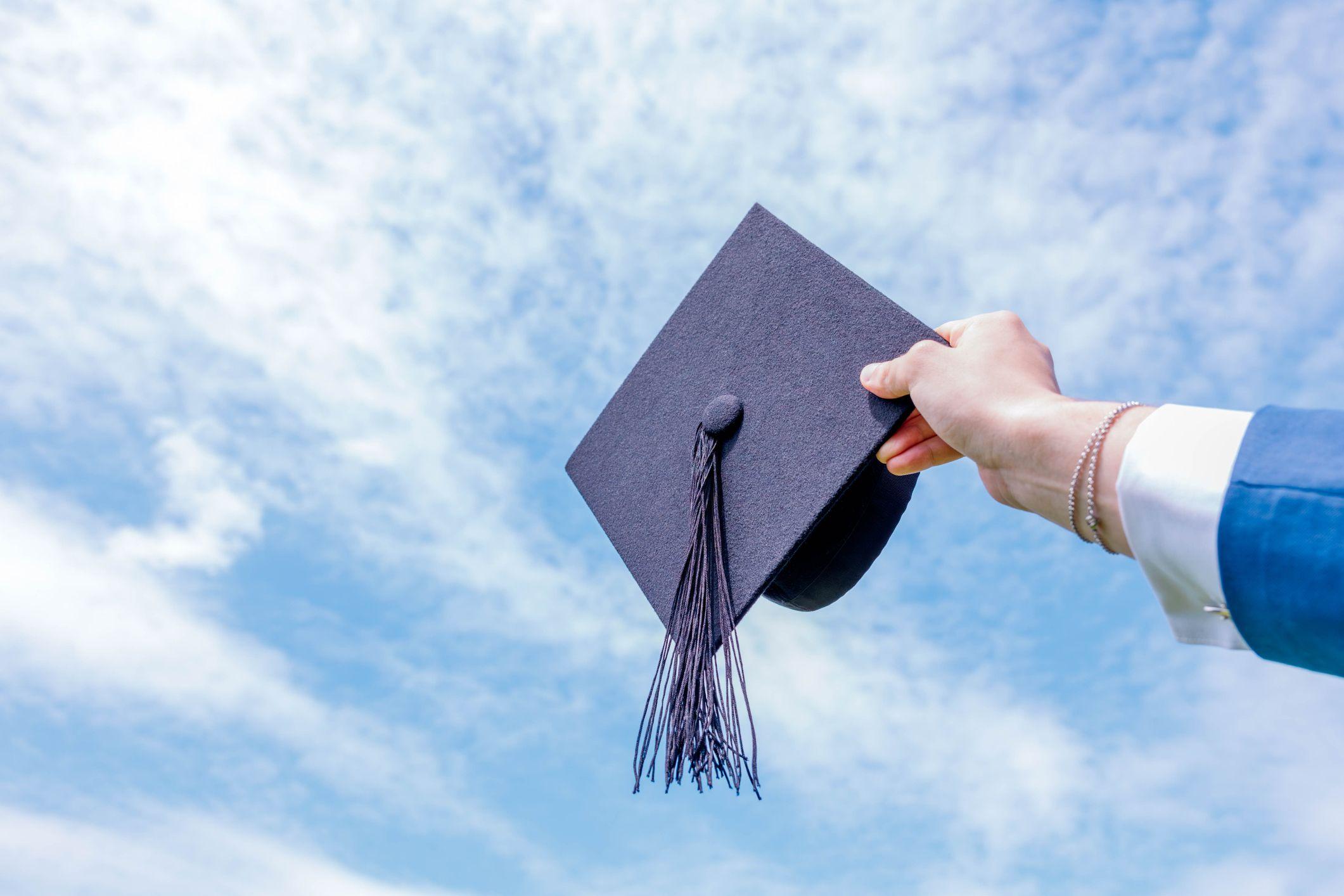 صورة طاقية تخرج من الجامعة يحملها شاب ويوجهها إلى السماء