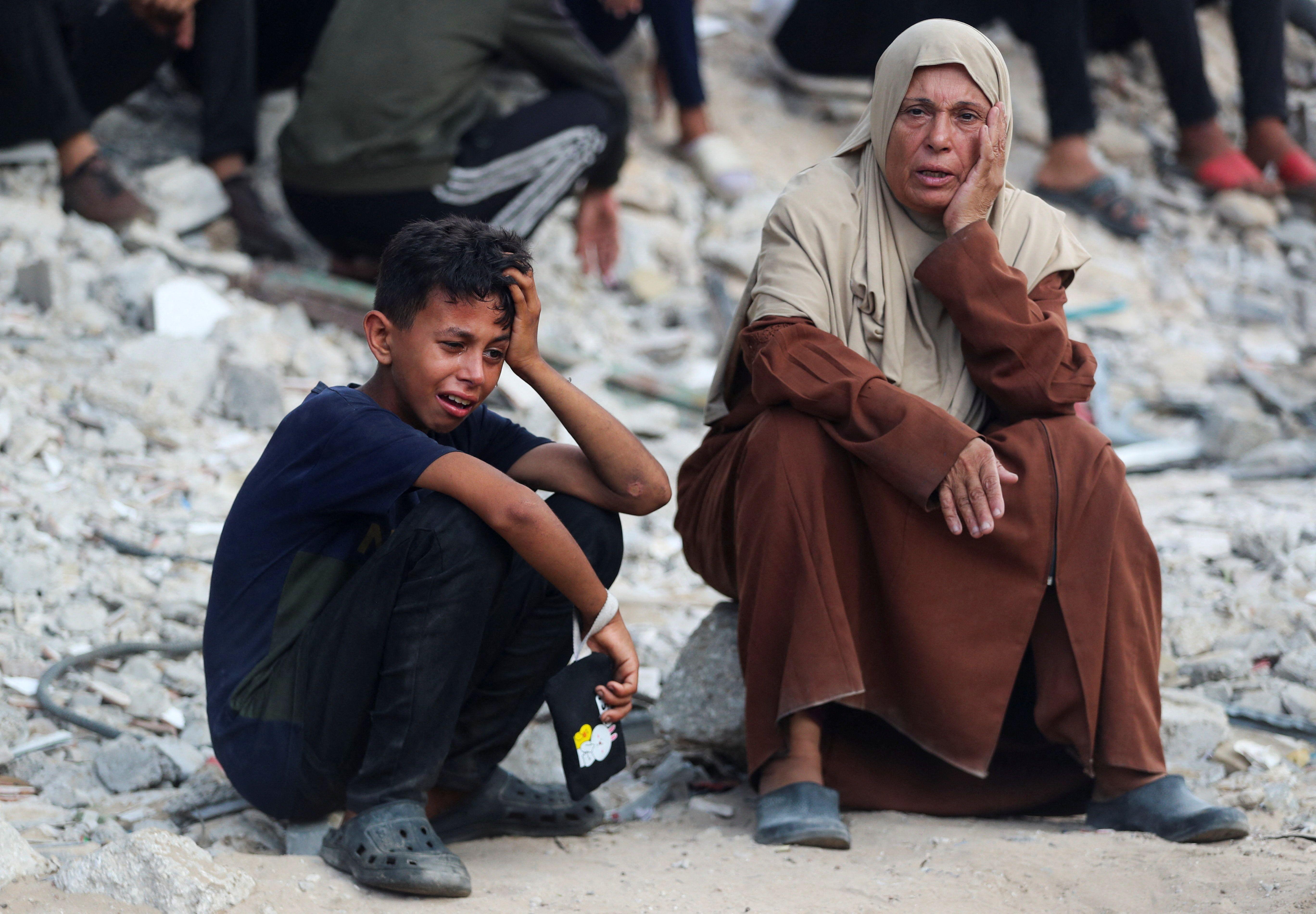 فلسطينيان قرب جنازة قتلى بنيران إسرائيلية أثناء محاولتهم تلقي المساعدات قرب مستشفى الشفاء بمدينة غزة