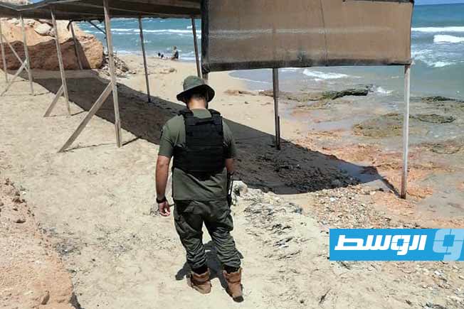 أحد عناصر فريق المباحث الجنائية أثناء مسح موقع اللغم بأحد مصايف تاجوراء. (جهاز المباحث الجنائية)