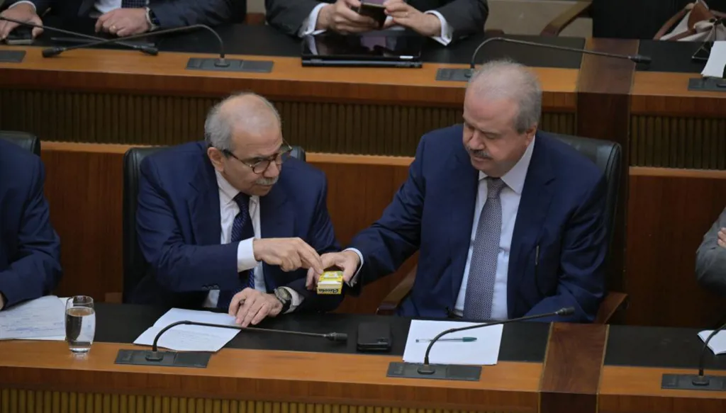 وزير المال ياسين جابر يقدم لرئيس الحكومة نواف سلام الحلوى خلال الجلسة النيابية أمس. (نبيل إسماعيل)