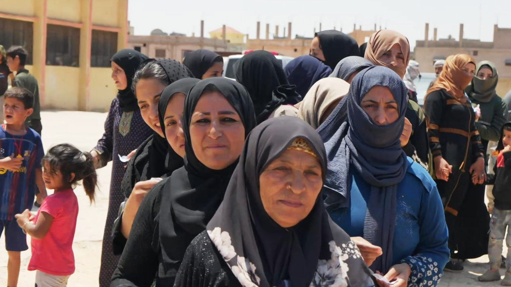 نساء بدويات نازحات يقفون في طابور انتظاراً للحصزل على المساعدات.