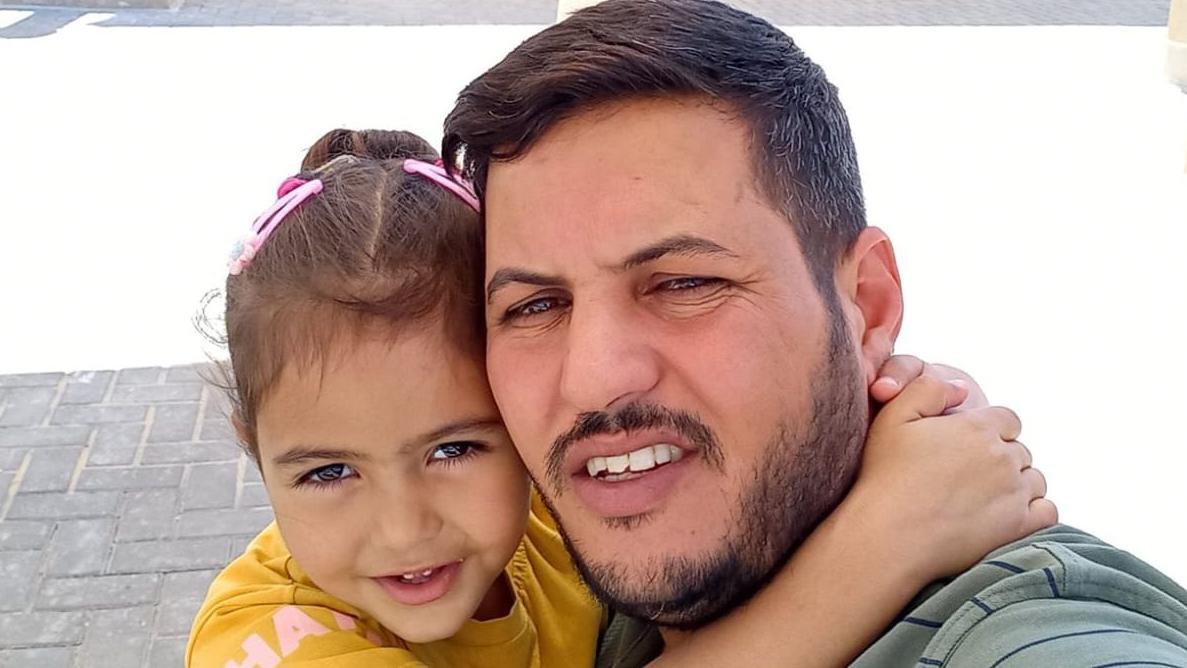 ميرا (يسار الصورة) تظهر مرتدية قميصا أصفر، وشعرها البني مربوط للخلف بمشابك شعر وردية، وتبتسم وهي تضع ذراعيها حول رقبة والدها. سعيد ذو شعر بني، وله لحية وشارب. وكلاهما ينظر إلى الكاميرا.